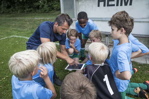 Trainer mit Tablet und jungen Fußballspielern auf dem Fußballplatz - WESTF24038