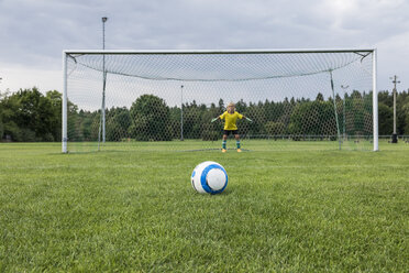Young football goalkeeper with ball on football ground - WESTF24039