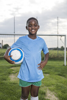 Portrait of smiling young football player holding ball on football ground - WESTF24041