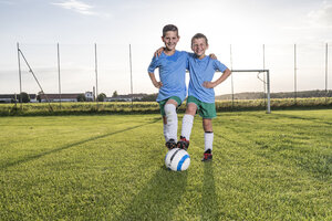 Lächelnde junge Fußballspieler, die sich auf dem Fußballplatz umarmen - WESTF24044