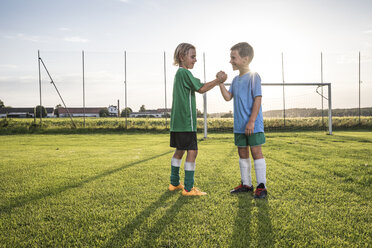Lächelnde junge Fußballspieler beim Händeschütteln auf dem Fußballplatz - WESTF24045