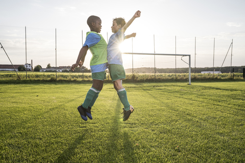 Junge Fußballspieler springen auf dem Fußballplatz, lizenzfreies Stockfoto