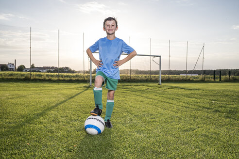 Porträt eines selbstbewussten jungen Fußballspielers mit Ball auf dem Fußballplatz - WESTF24050