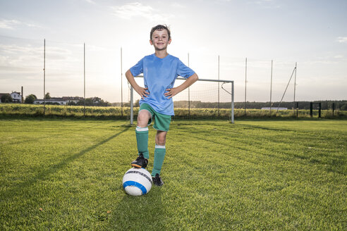 Portrait of confident young football player with ball on football ground - WESTF24050