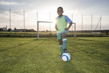 Porträt eines selbstbewussten jungen Fußballspielers mit Ball auf dem Fußballplatz - WESTF24051