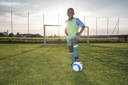 Portrait of confident young football player with ball on football ground - WESTF24051