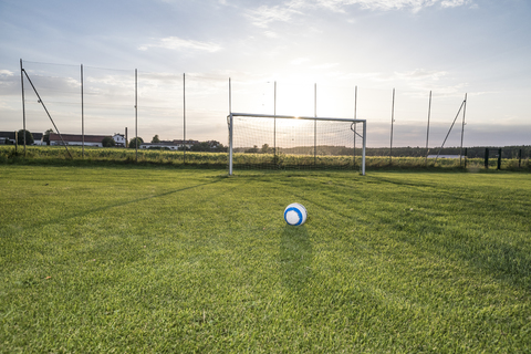 Auf dem Fußballplatz liegender Ball bei Sonnenuntergang, lizenzfreies Stockfoto