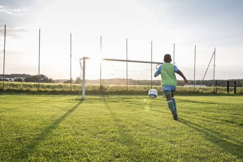 Young football player on football ground at sunset - WESTF24060