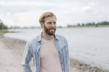 Germany, Duesseldorf, portrait of smiling man at riverside - KNSF03655