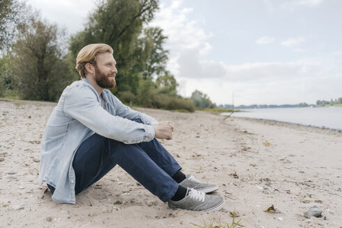 Deutschland, Düsseldorf, entspannter Mann sitzt am Strand und schaut auf die Aussicht - KNSF03657