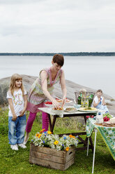 Frau bereitet Picknicktisch am Meer vor - FOLF08668