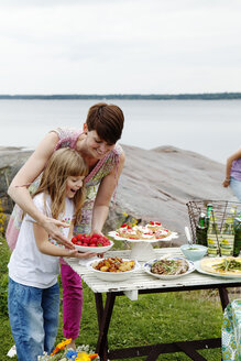 Frau bereitet Picknicktisch am Meer vor - FOLF08669