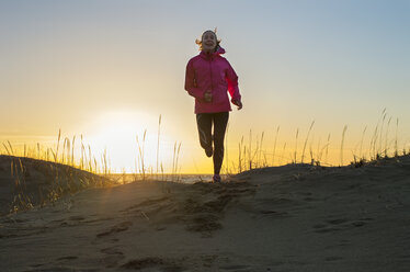 Junge Frau joggt am Strand bei Sonnenuntergang - FOLF08867