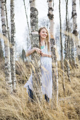 Smiling girl standing by birch tree in forest - FOLF08873
