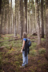 Frau trägt Rucksack, während sie im Wald steht - CAVF33947