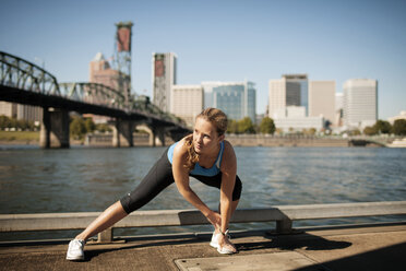 Determined woman exercising by lake in city - CAVF33954