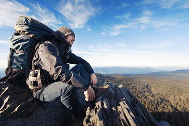 Successful male hiker sitting on mountain - CAVF33958