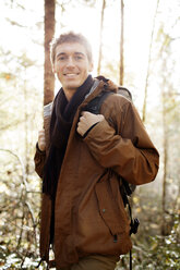 Portrait of happy male hiker standing in forest - CAVF33962