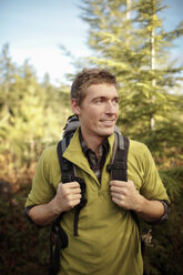 Male hiker looking away while standing in forest - CAVF33967