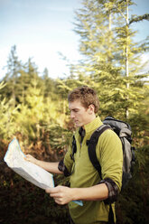Männlicher Wanderer, der im Wald stehend eine Karte liest - CAVF33968