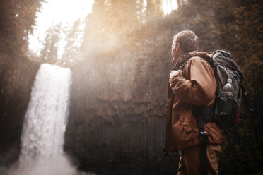 Seitenansicht eines Wanderers mit Rucksack und Blick auf einen Wasserfall - CAVF33974