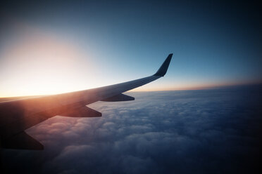 Beschnittenes Bild von Flugzeug fliegen in bewölktem Himmel bei Sonnenuntergang - CAVF33977