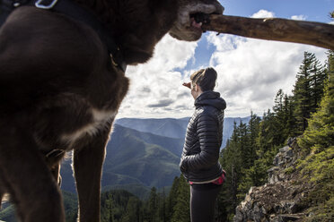 Frau betrachtet die Aussicht, während sie auf einer Bergklippe steht - CAVF33998