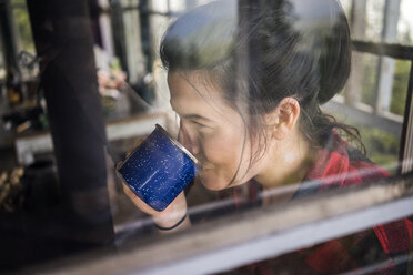 Nahaufnahme einer kaffeetrinkenden Frau durch ein Fenster gesehen - CAVF34015