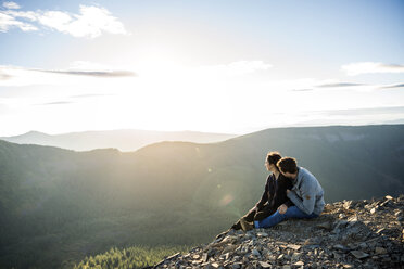 Couple sitting on mountain cliff and looking at view - CAVF34022