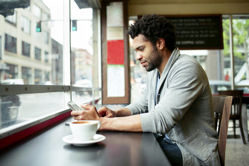 Seitenansicht eines Mannes, der einen Tablet-Computer am Tisch in einem Café benutzt - CAVF34039