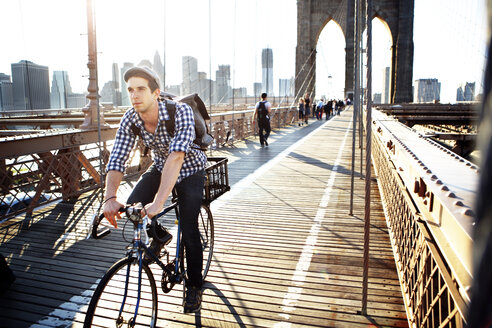 Mann fährt Fahrrad auf der Brooklyn Bridge gegen den klaren Himmel - CAVF34064