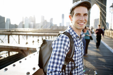 Porträt eines lächelnden Mannes, der auf der Brooklyn Bridge steht - CAVF34066
