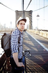 Thoughtful man holding bicycle and standing on Brooklyn Bridge - CAVF34067
