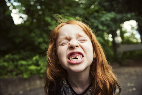 Close-up of girl clenching teeth at park - CAVF34095