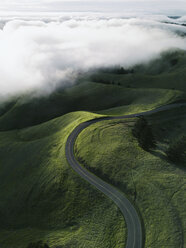 Aerial view of empty country road amidst green landscape against cloudy sky - CAVF34153