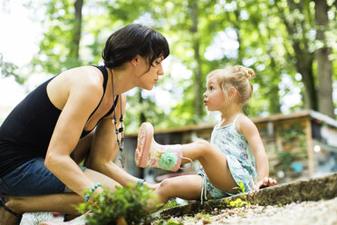 Side view of mother talking to daughter in backyard - CAVF34170