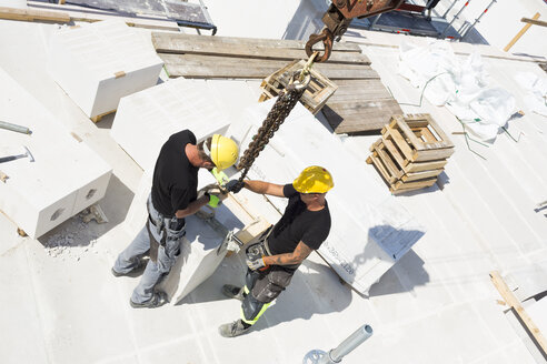 Construction workers adjusting blocks on construction site - FOLF09082
