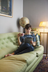 Frau mit digitalem Tablet auf Sofa - FOLF09129