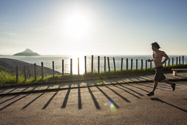 Mann läuft auf der Straße am Meer gegen den Himmel an einem sonnigen Tag - CAVF34240