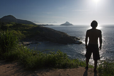 Rear view of silhouette man standing on cliff by sea against sky - CAVF34241