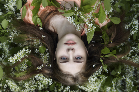 Overhead portrait of woman relaxing on plants at yard stock photo