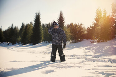 Boy standing on snow covered field against sky during sunset - CAVF34253