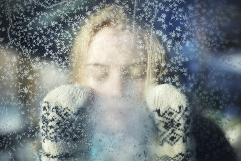 Nahaufnahme einer Frau mit geschlossenen Augen, gesehen durch Glas im Winter, lizenzfreies Stockfoto