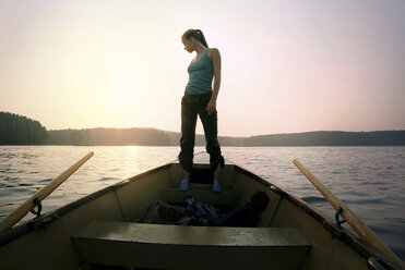 Full length of woman standing on boat against sky during sunset - CAVF34278