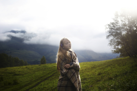 Woman wrapped in a blanket standing on field stock photo