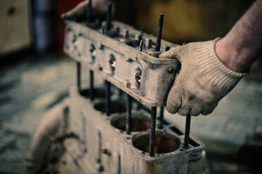 Abgeschnittene Hand eines Mechanikers, der eine Maschine in einer Werkstatt hält - CAVF34296