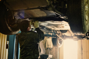 Rückansicht eines Mechanikers, der ein Fahrzeug in der Werkstatt repariert - CAVF34297