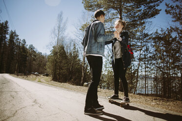 Low angle view of couple holding hands on country road during summer - CAVF34304