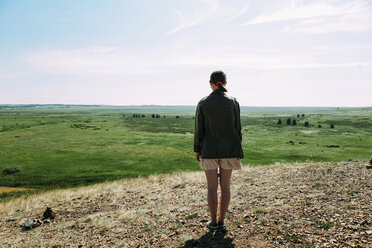 Rückansicht einer Frau, die auf einem Feld stehend gegen den Himmel blickt - CAVF34338