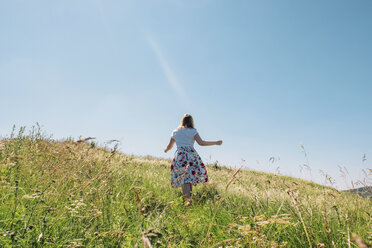 Rückansicht einer Frau auf einem grasbewachsenen Feld gegen den Himmel im Sommer - CAVF34343